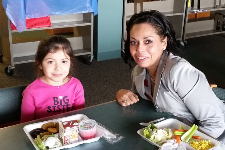 Teacher eats lunch with student.