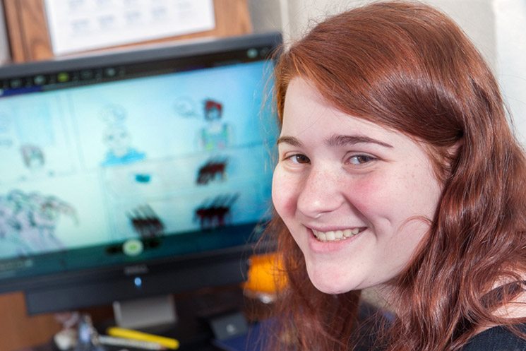 Student smiling while working at a computer.